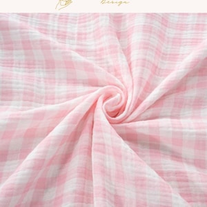 Könnte beinhalten: Nahaufnahme eines rosa-weiß karierten Stoffes mit weichem, strukturiertem Aussehen. Der Stoff ist gerafft und gewirbelt, wodurch ein Gefühl von Tiefe und Bewegung entsteht. Der obere Teil des Bildes trägt den Text "EXPLOREANDSHOP Design".