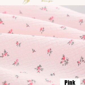 May include: Close-up of pink fabric with a delicate floral pattern. The fabric is a light pink color, with small red and green floral designs scattered across the surface. The word "Pink" is in a white rectangle.