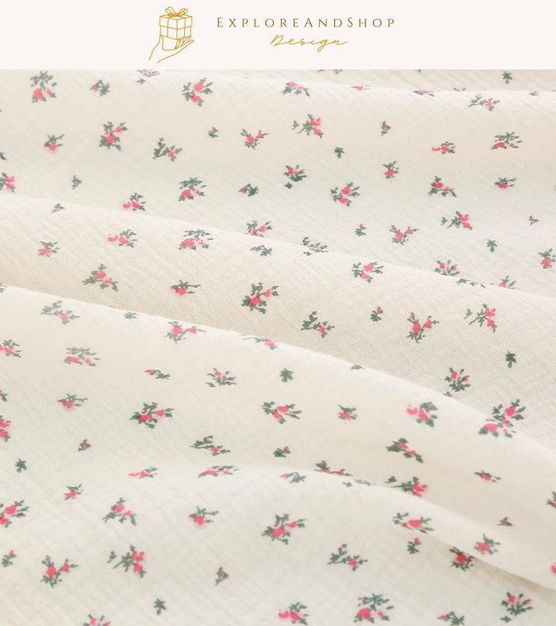 May include: Close-up of a cream-colored fabric with a delicate floral pattern. Tiny red and green floral clusters are scattered across the surface. The fabric is slightly wrinkled, creating soft shadows. The text "EXPLOREANDSHOP Design" is in the upper right corner.