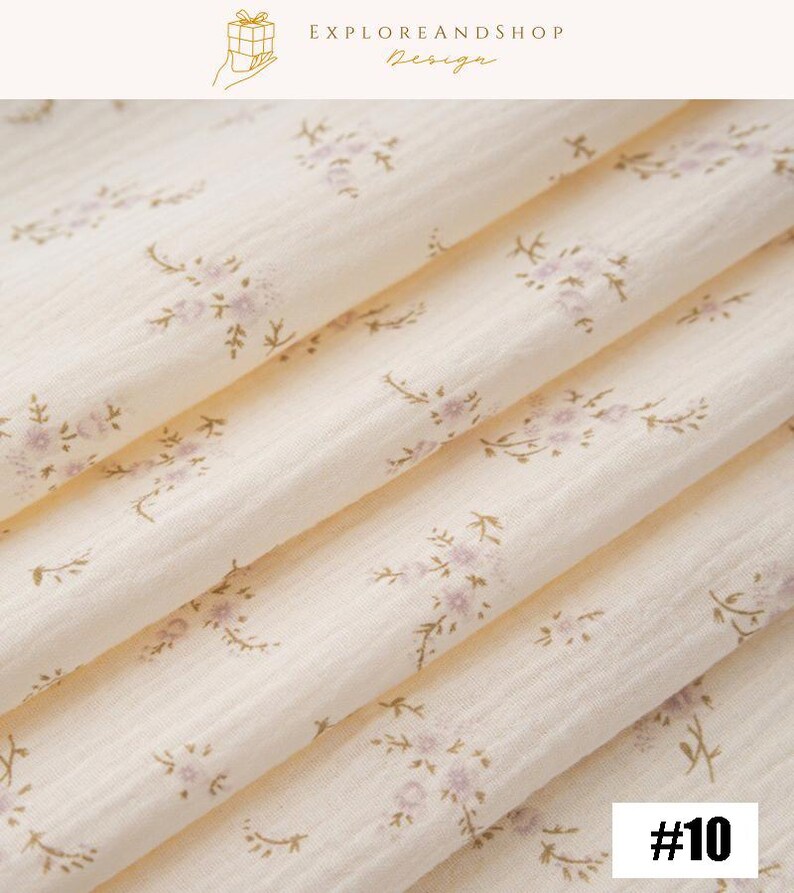 May include: Close-up of a cream-colored fabric with a delicate floral pattern in light purple and brown. The fabric is folded, showing the texture and design. The number "#10" is in the bottom right corner. The top right corner has the text "EXPLOREANDSHOP Design".