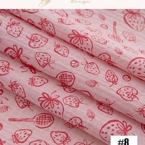 May include: Pink fabric with a repeating pattern of red strawberries and tennis rackets. The fabric is folded, showing the texture and design. The text "#8" is in the bottom right corner. The words "EXPLOREANDSHOP Design" are at the top.