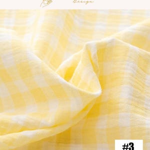 May include: Close-up of a soft, yellow and white checkered fabric. The fabric is draped, showing folds and texture. The text "#3" is visible in a white rectangle in the bottom right corner. The top right corner has the text "EXPLOREANDSHOP Design".
