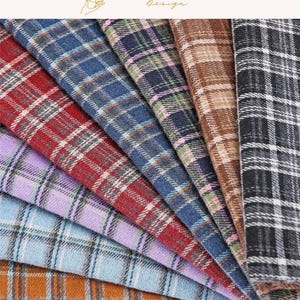 Pode incluir: Uma coleção de amostras de tecido com vários padrões xadrez em vermelho, azul, verde, castanho, preto, roxo e azul claro. O texto EXPLOREANDSHOP Design é visível no topo. Cada peça de tecido exibe um design xadrez distinto.