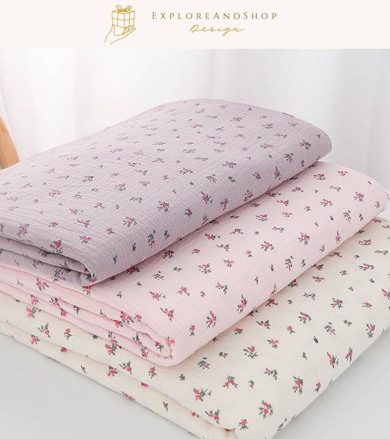 May include: Three folded fabric pieces in shades of lavender, pink, and cream, each adorned with a delicate floral pattern. The fabric is soft and appears to be lightweight, suitable for various crafting projects or home decor.