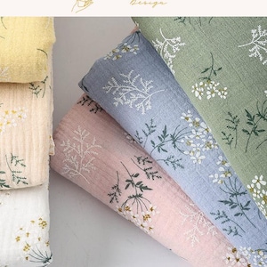 May include: Close-up of folded fabric in pastel shades of yellow, pink, blue, and green. Each fabric features a delicate white floral pattern. The top left corner shows the text "EXPLOREANDSHOP Design."
