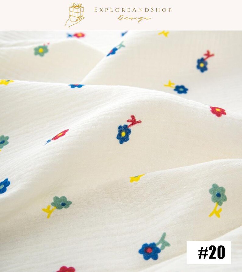 May include: Close-up of a white fabric with a textured surface, adorned with small, colorful floral patterns. The flowers are in shades of blue, red, yellow, and green. The number "#20" is visible in the bottom right corner. The top right corner has the text "EXPLOREANDSHOP Design".