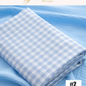 May include: A folded, light blue and white gingham patterned fabric. The fabric is layered on top of a solid light blue fabric. The image includes the text "EXPLOREANDSHOP Design" and the number "#2" in a white box.