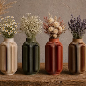 May include: Four decorative vases in beige, green, red-orange, and tan, each holding different dried flowers. The vases have a ribbed design and are arranged on a wooden surface, creating a rustic and natural aesthetic.