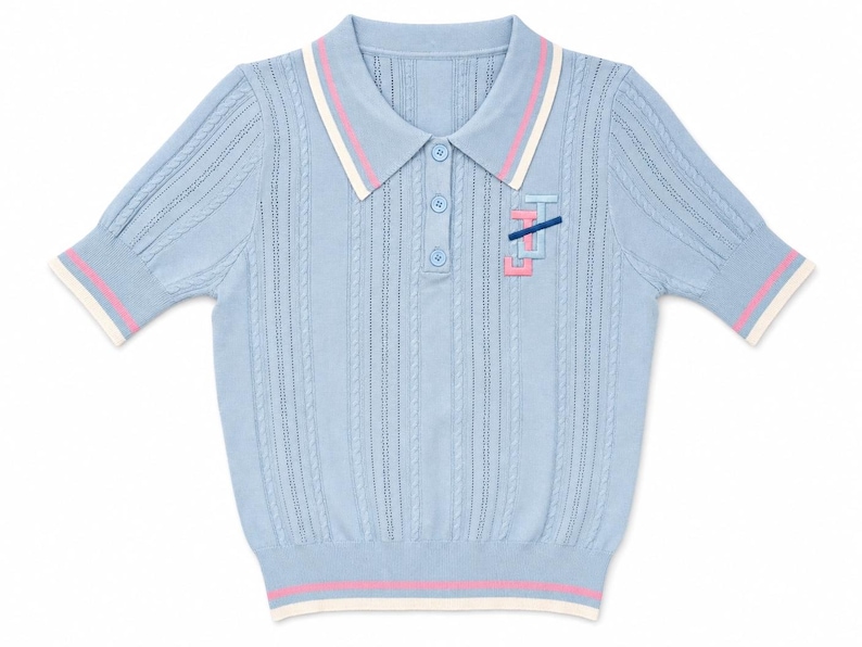 May include: A light blue short-sleeved polo shirt with a cable knit texture. The collar and sleeve cuffs feature white and pink stripes. A small embroidered logo in pink and dark blue is positioned on the left chest area below the collar.