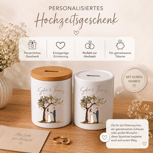 May include: Two white ceramic money boxes with a wooden lid on one, featuring a printed illustration of a couple under a tree and the text "Sofie & Thomas". The image includes German text labels and a small card with the text "Alles Liebe zur Hochzeit".