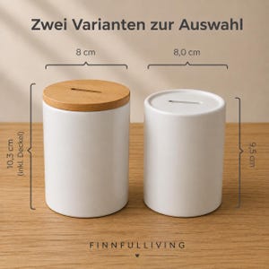 May include: Two cylindrical white ceramic coin banks with coin slots. The left bank has a light wood lid and measures 8 cm in diameter and 10.3 cm in height. The right bank is all white, measuring 8.0 cm in diameter and 9.5 cm in height. Text reads: Zwei Varianten zur Auswahl, FINNFULLIVING.