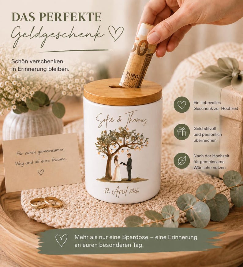 May include: A white ceramic money box with a wooden lid featuring a printed illustration of a couple under a tree with string lights, the names Sofie & Thomas, and the date 27. April 2026. The container is cylindrical with a coin slot on top.