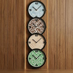 Puede incluir: Cuatro relojes de pared redondos con marcos negros se muestran verticalmente en una pared de madera. Cada esfera presenta un diseño único: olas azules, un árbol, círculos concéntricos y formas orgánicas verdes. Los relojes tienen manecillas y números negros.
