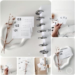 May include: A set of white rectangular calendar cards with black text and numbers, featuring dates for 2023. The cards measure 8.9 by 5.1 inches and are displayed alongside a disc-bound planner, dried flowers, and a beige fabric organizer.