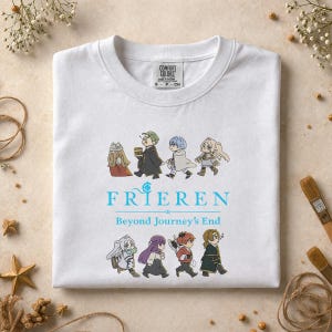 May include: White crew neck sweatshirt featuring a cartoon illustration of characters walking. The word "FRIEREN" is printed in light blue, with "Beyond Journey's End" below. The sweatshirt has a Comfort Colors tag.