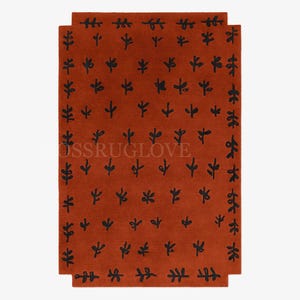 May include: A rectangular terracotta-colored rug with a repeating pattern of black leaf-like shapes. The rug has a border of stylized black leaves and a central field of smaller leaf motifs.
