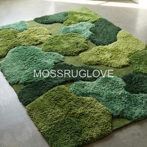 May include: A rectangular rug with a moss-like design. The rug features various shades of green, with cloud-like shapes in different textures and tones. The text "MOSSRUGLOVE" is visible on the rug.