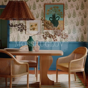 Puede incluir: Un comedor con una mesa y sillas de madera con respaldos tejidos. Una l&aacute;mpara colgante tejida cuelga encima. Las paredes est&aacute;n decoradas con papel pintado con estampado de helechos y un acento azul. Obras de arte y un jarr&oacute;n con ramas est&aacute;n sobre la mesa. El texto "MOSSRUGLOV" es visible.
