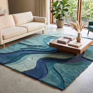 Könnte beinhalten: Ein rechteckiger Teppich mit einem geschichteten, wellenförmigen Design in verschiedenen Blau-, Türkis- und Grüntönen. Der Teppich hat eine strukturierte Hoch-Tief-Flor-Konstruktion mit fließenden, organischen Kurven, die Tiefe erzeugen.