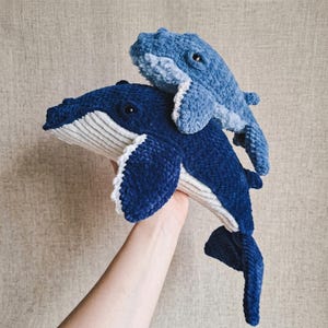 Puede incluir: Una taza de cerámica blanca con un asa negra y el texto "But First, Coffee" en negrita negra. La taza se encuentra sobre un fondo borroso, sugiriendo un ambiente acogedor.