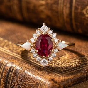 Anello con pavé di rubini ovali, fascia in stile oro vintage, dettagli scintillanti.