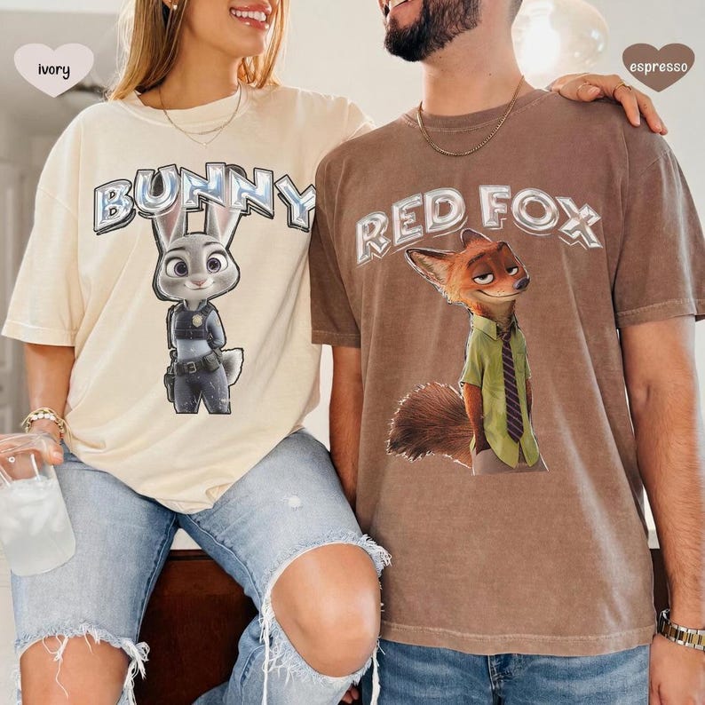 以下が含まれることがあります： ズートピアのキャラクターが描かれた、アイボリーとエスプレッソの2枚のTシャツ。アイボリーのシャツには「BUNNY」の文字とジュディ・ホップスが描かれています。エスプレッソのシャツには「RED FOX」の文字とニック・ワイルドが描かれています。どちらのシャツもヴィンテージスタイルです。