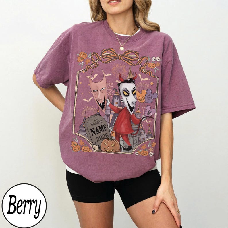 K&ouml;nnte beinhalten: Beerenfarbenes T-Shirt mit einem Halloween-Motiv. Das Design zeigt Zeichentrickfiguren, einen Grabstein mit dem Text "NAME 2026" und K&uuml;rbisse. Das Shirt hat eine lockere Passform und kurze &Auml;rmel.
