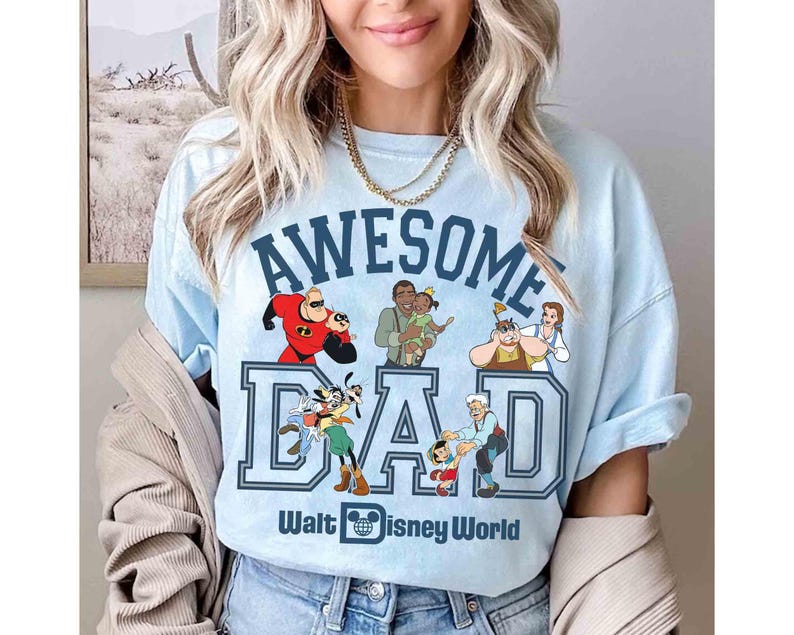 May include: Light blue t-shirt with the words "AWESOME DAD" in navy blue block letters, featuring Disney characters. The shirt also includes the text "Walt Disney World" and a Disney logo.
