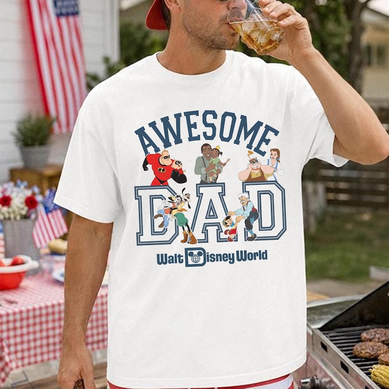May include: White t-shirt with the text "AWESOME DAD" in blue, featuring Disney characters. The shirt includes images of Mr. Incredible, Goofy, and other characters. Below the text is "Walt Disney World".