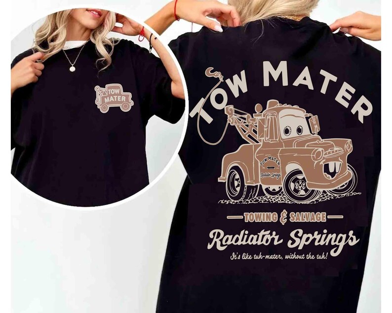 May include: A black t-shirt featuring a graphic of the character Tow Mater on the back with the text Tow Mater, Towing & Salvage, Radiator Springs, and It's like tuh-mater, without the tuh. A smaller version of the truck is printed on the front.