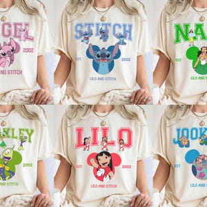 May include: Cream-colored t-shirts featuring various characters from "Lilo & Stitch." Each shirt displays a different character's name in a collegiate font, along with the text "EST 2002" and "LILO AND STITCH."