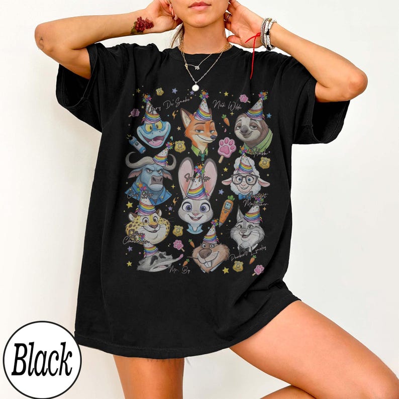 May include: Black t-shirt featuring a colorful graphic of cartoon animal characters wearing party hats. The design includes the text "Dr. Snuggles" and "Nick Wilde". The shirt has a relaxed fit.