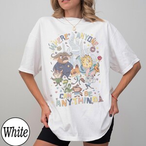 May include: White t-shirt featuring a colorful graphic of characters from the animated film "Zootopia." The design includes the text "WHERE ANYONE CAN BE ANYTHING" in a playful font, with various animal characters.