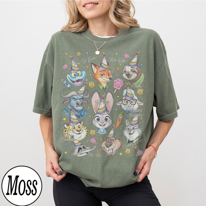May include: An olive green t-shirt featuring a colorful graphic of various cartoon animal characters wearing party hats. The design includes a frog, fox, sloth, bunny, and others. The shirt has the word "Moss" in a circle at the bottom.