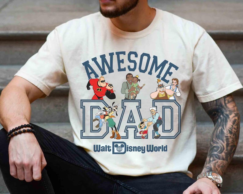 May include: Cream-colored t-shirt with the words "AWESOME DAD" in blue block letters, featuring Disney characters. The phrase "Walt Disney World" is printed below the word "DAD".