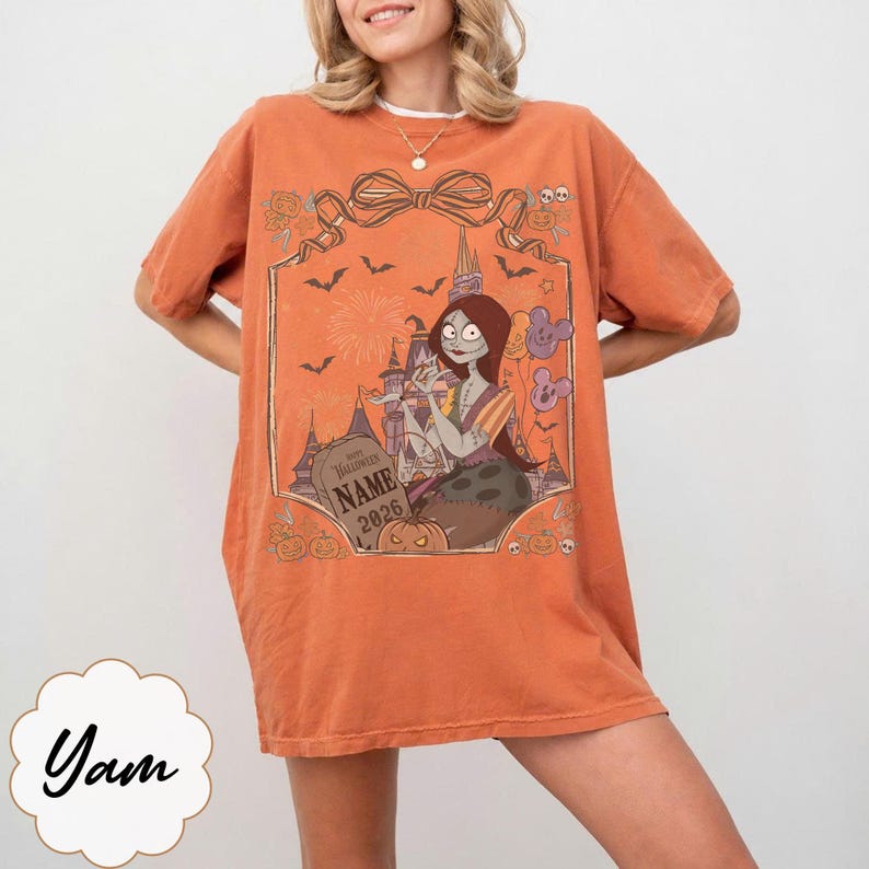 K&ouml;nnte beinhalten: Orangefarbenes T-Shirt mit einer Grafik einer Figur aus The Nightmare Before Christmas. Das Design beinhaltet einen Grabstein mit dem Text "Halloween Name 2026" und andere Halloween-Elemente. Das Shirt hat kurze &Auml;rmel und eine lockere Passform.