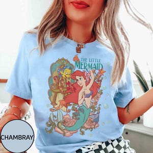 Pu&ograve; includere: T-shirt azzurro con grafica di Ariel de La Sirenetta, con la scritta "THE LITTLE MERMAID". Il design include Ariel, Flounder ed elementi floreali. La maglietta &egrave; realizzata in materiale morbido.