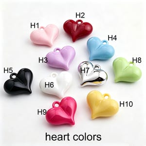 May include: Ten heart-shaped charms labeled H1 through H10, featuring a glossy finish in various colors including pink, red, light blue, purple, black, white, silver, light green, magenta, and yellow, each with a small loop for attachment.