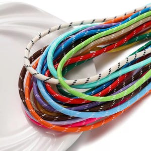 May include: A collection of multi-colored braided cords featuring a woven texture. The cords are available in various vibrant hues including white, blue, green, red, orange, purple, and brown, each accented with small, repeating black or white dashes.