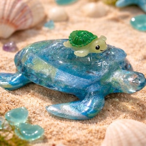 Peut inclure: Ensemble de trois mugs en céramique avec un glaçage moucheté de couleur crème. Chaque mug présente un motif peint à la main différent : une feuille bleue et verte, une fleur jaune et une baie rouge. Les mugs ont une forme simple et arrondie avec une anse confortable.