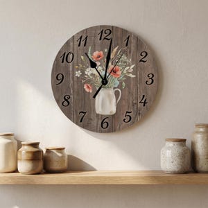 May include: A round wall clock with a brown wood-plank background featuring a printed illustration of a white ceramic pitcher filled with colorful wildflowers, including red poppies, and black numerals from one to twelve with black clock hands.