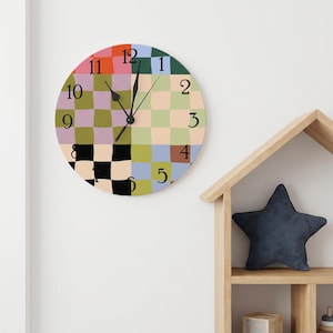 May include: A round wall clock featuring a multi-coloured, distorted checkerboard pattern in shades of red, green, blue, yellow, black, and purple. The clock face displays black Arabic numerals from 1 to 12 and has three black clock hands.