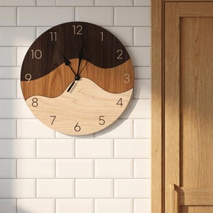 May include: A round wall clock featuring a three-tone wood design with wavy horizontal sections in dark brown, medium brown, and light beige. The clock face displays thin black numerals from one to twelve and two black clock hands at the center.