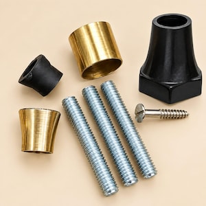 Puede incluir: Un kit de montaje de hardware que contiene tres varillas roscadas de metal plateado, un tornillo de cabeza plana plateado, dos componentes cilíndricos de color latón, una pequeña funda de goma negra y una base cónica negra grande.