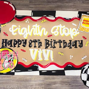 May include: A rectangular birthday banner featuring a tan center with wavy red borders, black and white checkered corners, and the text "Eighth Stop Happy 8th Birthday Viv!". It includes illustrations of red circles, daisies, and a bag of Beaver Nuggets.