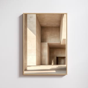 May include: Framed print featuring a modern architectural design. The image shows a building with geometric forms and a figure walking in the distance. The building is made of beige stone, with sunlight creating shadows.