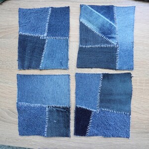 May include: Four square fabric coasters made from various shades of blue denim patches joined together with visible white whipstitching. Each coaster features a unique arrangement of denim scraps in light, medium, and dark blue tones.