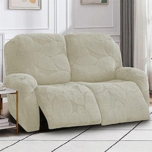 May include: Cream-colored recliner sofa cover with a leaf pattern. The cover is designed to fit a two-seat recliner, offering protection and a decorative touch. The leaf pattern adds a subtle, natural element to the furniture.