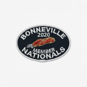 Peut inclure: Écusson ovale avec l'inscription "BONNEVILLE 2020 MEMBER NATIONALS" en blanc sur fond bleu marine. Un dessin de voiture de course rouge est au centre. L'écusson a une bordure blanche.