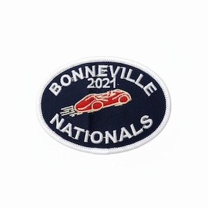 May include: Oval patch with the text "BONNEVILLE NATIONALS 2021" in white lettering on a navy blue background. A red race car graphic is in the center. The patch has a white border and is likely an embroidered patch.